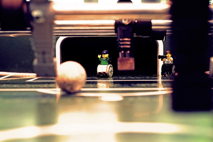 Foto: Legofigur im Rollstuhl steht im Tor eines Kickertisches