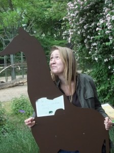 Foto: Ich hinter einer hölzernen Babygiraffe, man sieht nur meinen Oberkörper