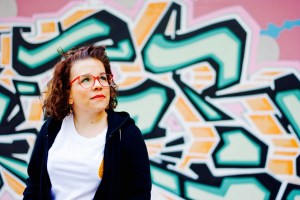 Foto: Ninia LaGrande vor einer Wand mit Graffiti