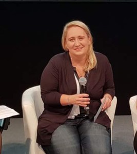 Foto: Nadine kurz vor der Podiumsdiskussion auf der REHACARE 2018. Sie sitzt auf einem Stuhl und hält ein Mikrofon in der Hand.