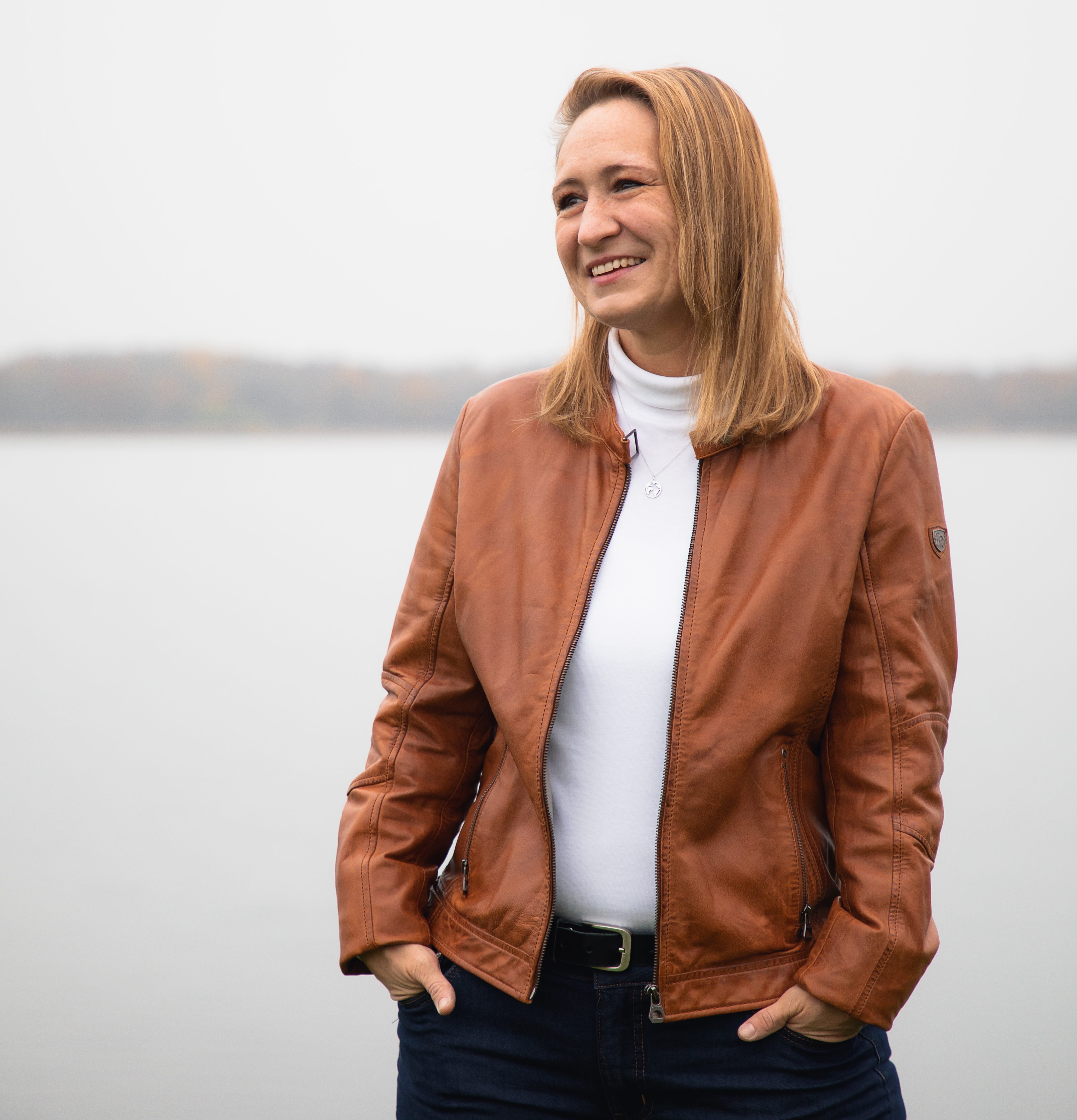 Nadine steht lässig am Hafen und lächelt an der Kamera vorbei